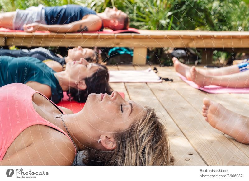 Yoga trainer meditating in Savasana position during class with instructor woman people yoga corpse savasana lotus pose camp meditate relax healthy wellness