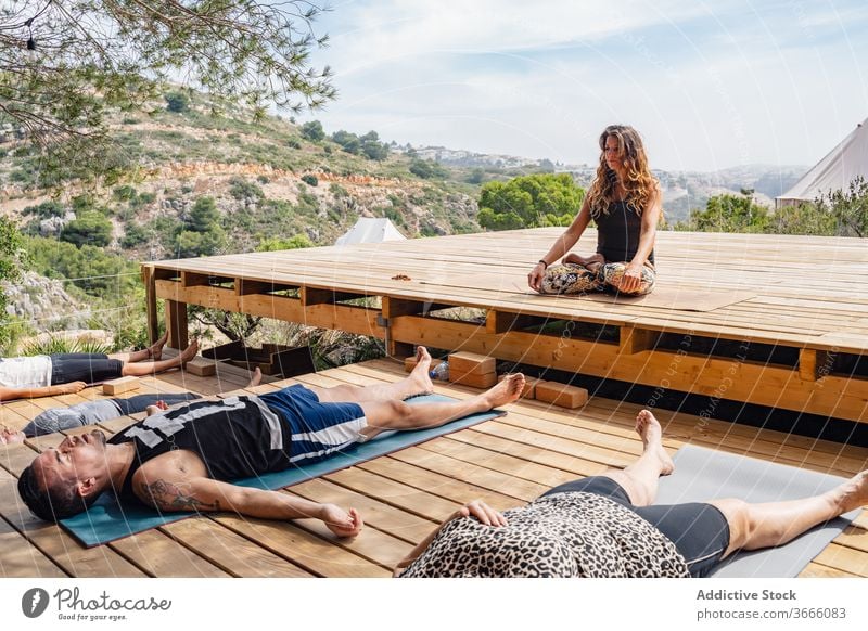 Group of yoga trainers meditating in Savasana position during class with instructor people corpse savasana lotus pose camp meditate recreation relax healthy
