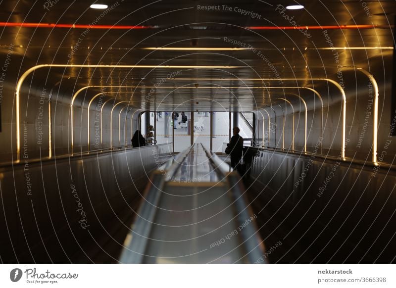 Illuminated escalator tube with silhouettes of people day indoors inside interior architecture traveling traveller electricity using power illuminated lit up