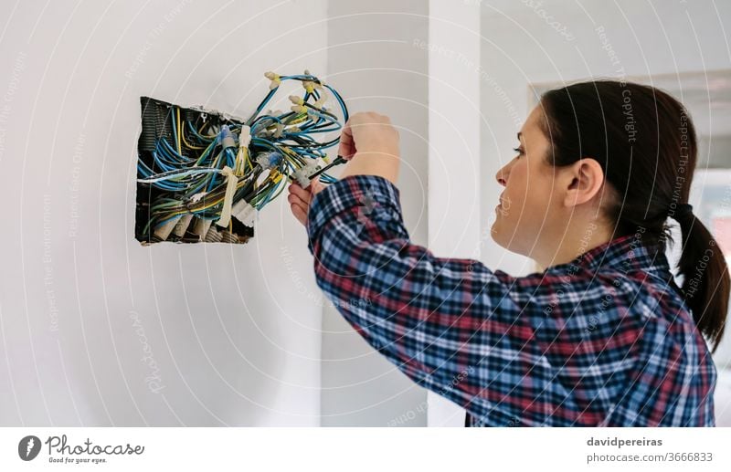 Electrician working on the electrical installation of a house electrical technician female electrician screwdriver connecting electric wire corrugated pipe
