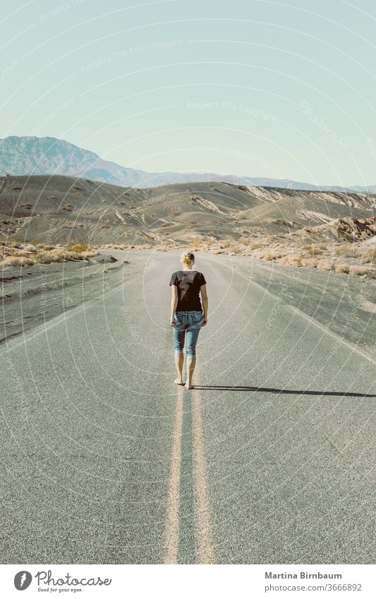 A woman walking barefooted on an empty road in the Death Valley one person caucasian woman death valley the way forward vanishing point freedom landscape travel