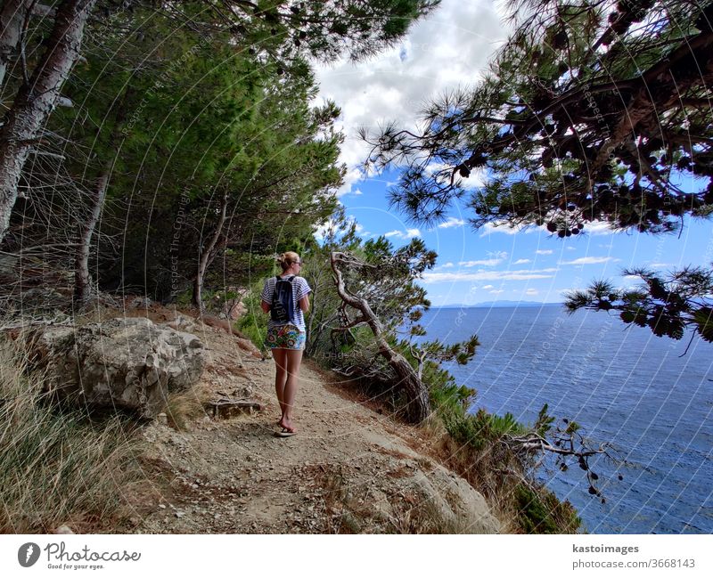 Young woman on summer vacation walking on a coastal path trough pine forest conecting small coves of Adriatic Mediterranean sea. girl Coast Ocean Woman nature