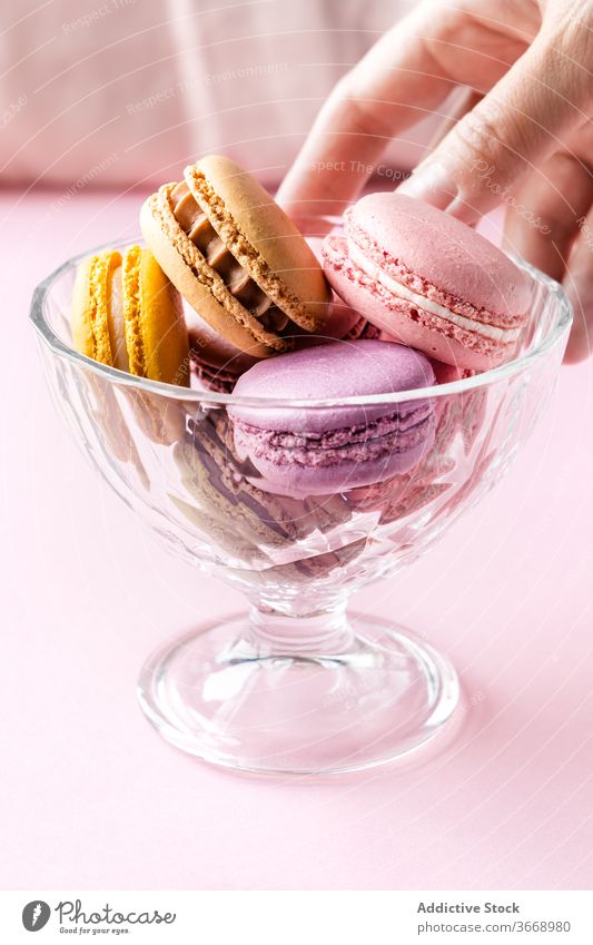 Woman taking delicious macaroons from bowl macaron tasty woman colorful palatable pastry food kitchen female glass fresh yummy home dessert meal sweet gourmet