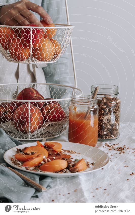 Crop person at table during breakfast healthy granola morning bowl fruit organic yogurt food fresh natural vitamin delicious meal diet apron vegetarian tasty