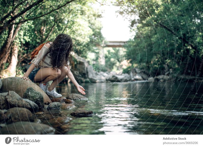 Traveling woman near river in forest travel tourist summer vacation water holiday serene calm female nature stone shore weekend harmony tranquil peaceful coast