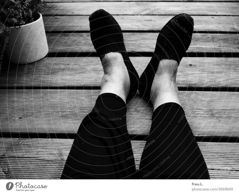 Shoes, feet, leggings, legs and a dress lie flat on the wooden grates of a roof terrace. The rest of the woman is not to be seen. Woman Sit Balcony Relaxation