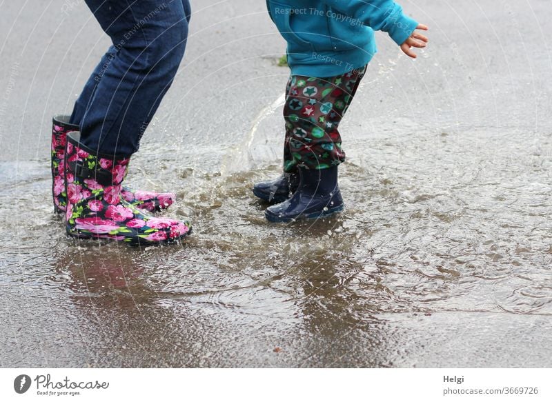 Puddle fun - mother and child have fun jumping into the puddle Mother Child Detail Legs Rubber boots Jump splat Joy Splash Inject Water Wet Rain Playing