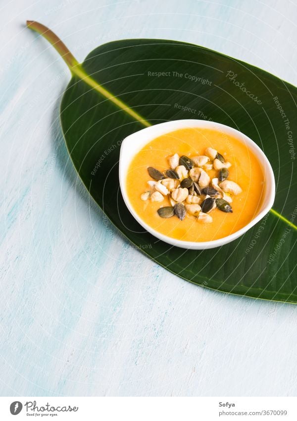 Pumpkin creamy soup served on green leaf pumpkin bowl food healthy meal vegetable bean white cannellini italian dinner yellow cuisine rustic lunch vegetarian