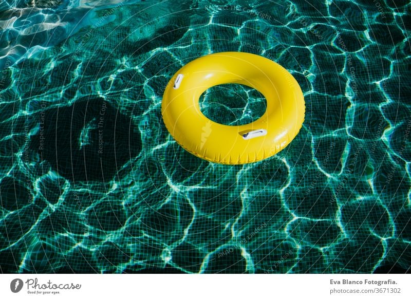 yellow inflatable donuts floating in a swimming pool. Nobody. Summer time concept nobody summer blue water toy ring preserver emergency colors circle abstract