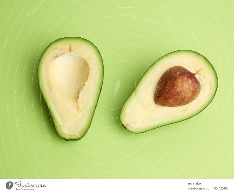 half ripe green avocado with a brown pit on a green background - a