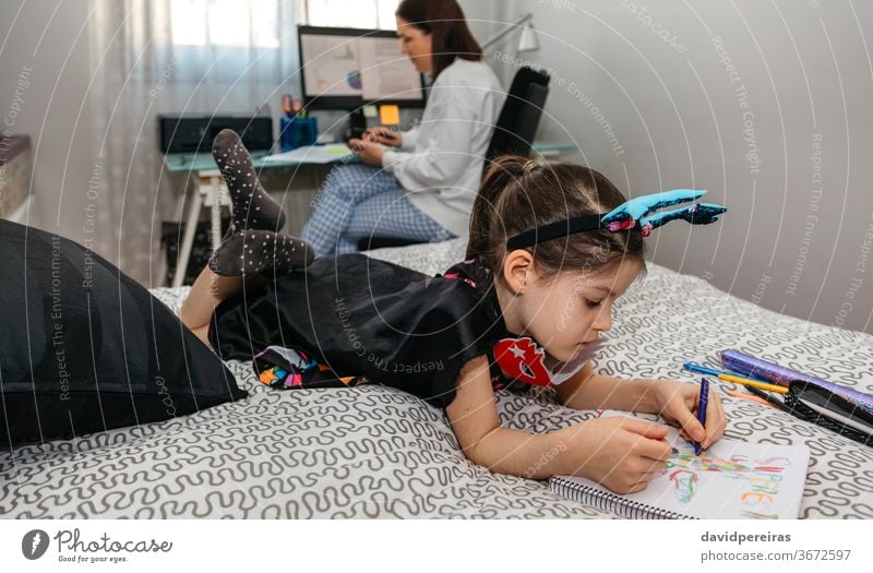 Girl drawing in disguise while her mother teleworking home office work family reconciliation girl bedroom covid-19 coloring telecommuting life balance 2019-ncov