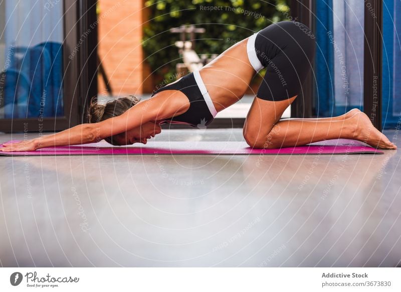 Fit woman stretching back on yoga mat at home - a Royalty Free