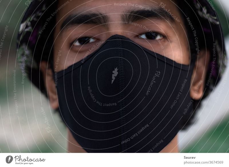 Close Up Portrait of a Young Millennial wearing a Black Protective Mask to Prevent Covid-19 Virus Infection. The New Normal during World Pandemic. new normal