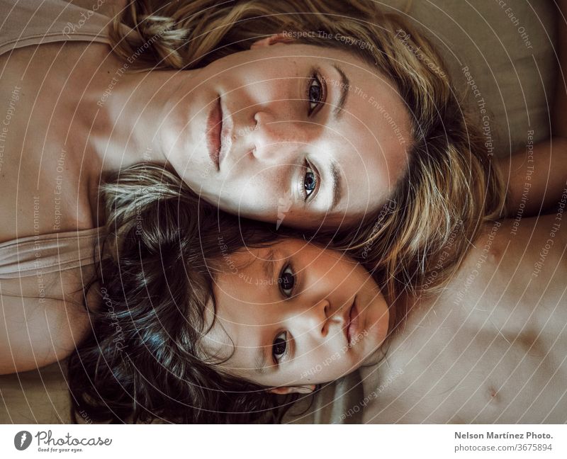 Portrait of mom and daughter lying down in the bed, hispanic and caucasian. High view. portrait love family eyes beautiful kid high view mommy Love
