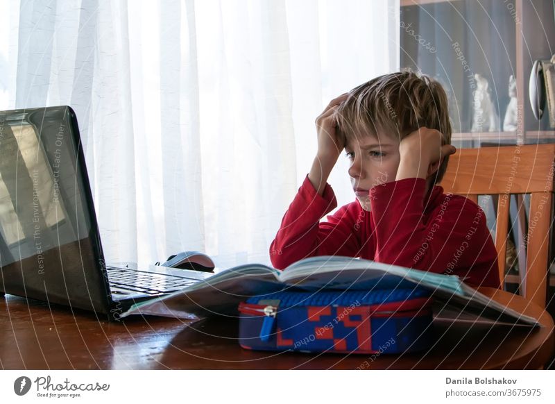 School kid in self isolation using laptop for homework, Social Distance learning online education during coronavirus epidemic. Cute boy studies and does school homework at home during quarantine