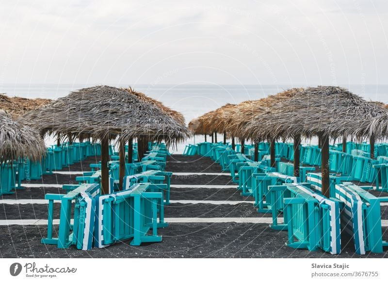 Sunbeds and parasols on blank sand beach. Perissa, Santorini island, Greece aegean beachside black blue caldera coast coastline cyclades destination europe