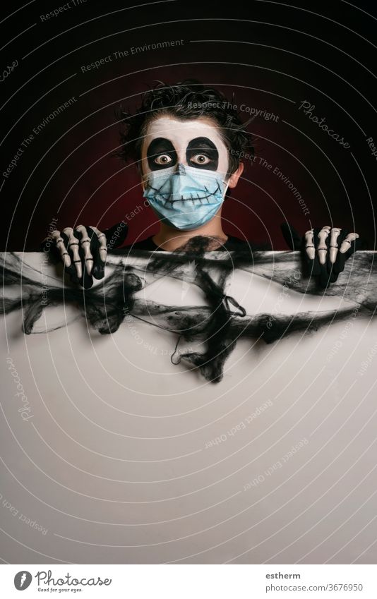 Happy Halloween. kid wearing medical mask in a skeleton costume holding blank board child halloween coronavirus covid-19 party fun skull fear social distancing