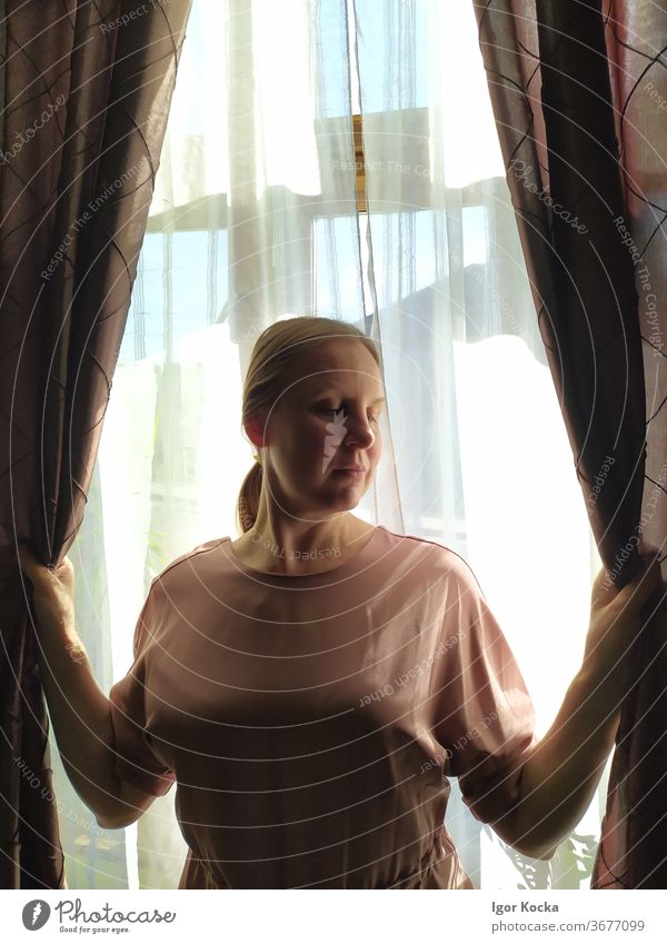 Front View of Woman Holding Curtains curtains Window holding Beautiful shyness Brown backlighting looking down Lifestyle Drape