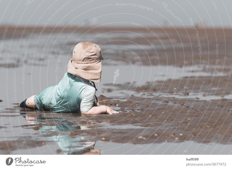 the little boy lies comfortably in the mudflats and looks around Toddler Child Playing Boy (child) Beach Mud flats Low tide North Sea Ocean Coast Water Horizon
