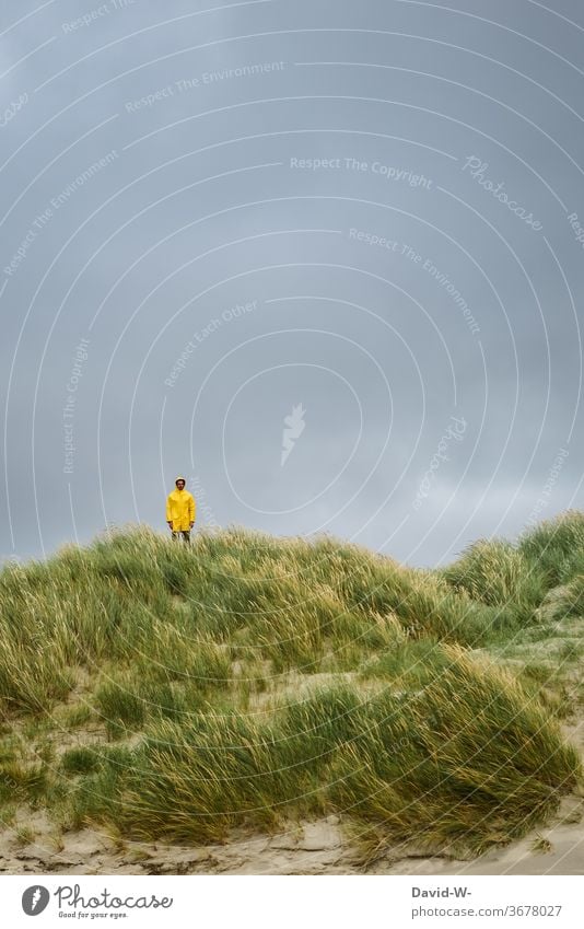 Man in yellow raincoat stands ready in the dunes for the storm that is about to arrive friesennerz Dike Thunder and lightning Storm Wet downpour Yellow vacation