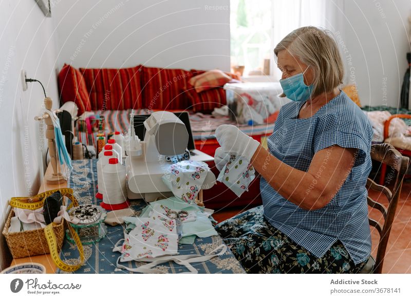 Senior woman sewing protective masks at home coronavirus artisan covid handmade pandemic homemade prevent female elderly senior mature covid19 infection