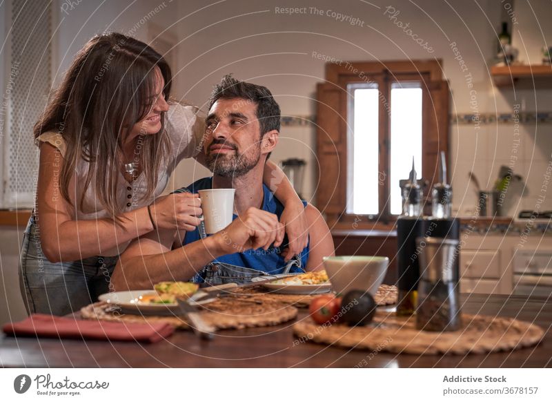 Content couple embracing in kitchen breakfast embrace morning delicious together relationship food tasty wife husband home happy table cheerful love romantic