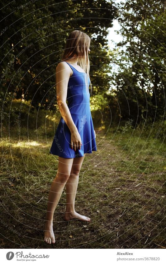 Lateral portrait of a young woman in nature in front of a forest ...