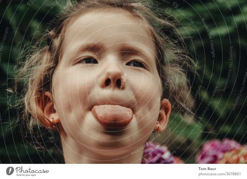 Sassy girl sticks out her tongue Brash Tongue stick out one's tongue show tongue portrait Blonde Blonde hair Stick out Face Colour photo Child Mouth Funny Joy