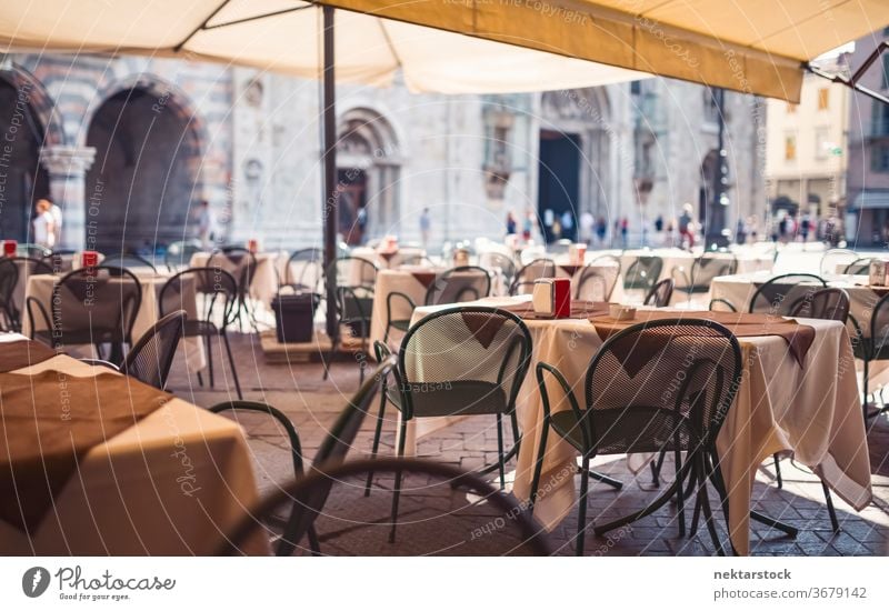 Outdoor Restaurant Seats on Sunny Day in Milan Table chair restaurant outdoor street cafe sunny unrecognizable people focus on foreground shallow depth of field