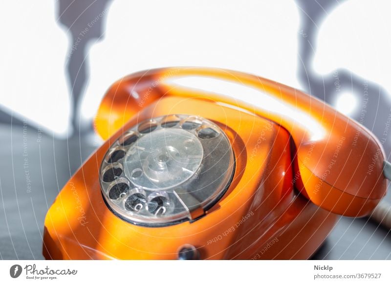 Telephoning - orange telephone "FeTAp 615" in orange with dial and handset (retro) in bright sunlight Telephone dial telephone Rotary dial Retro Orange fetap