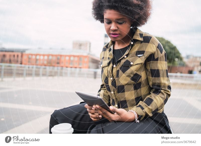 Afro american latin woman using digital tablet afro people young female technology coffee casual computer person beautiful bench internet city lifestyle smile