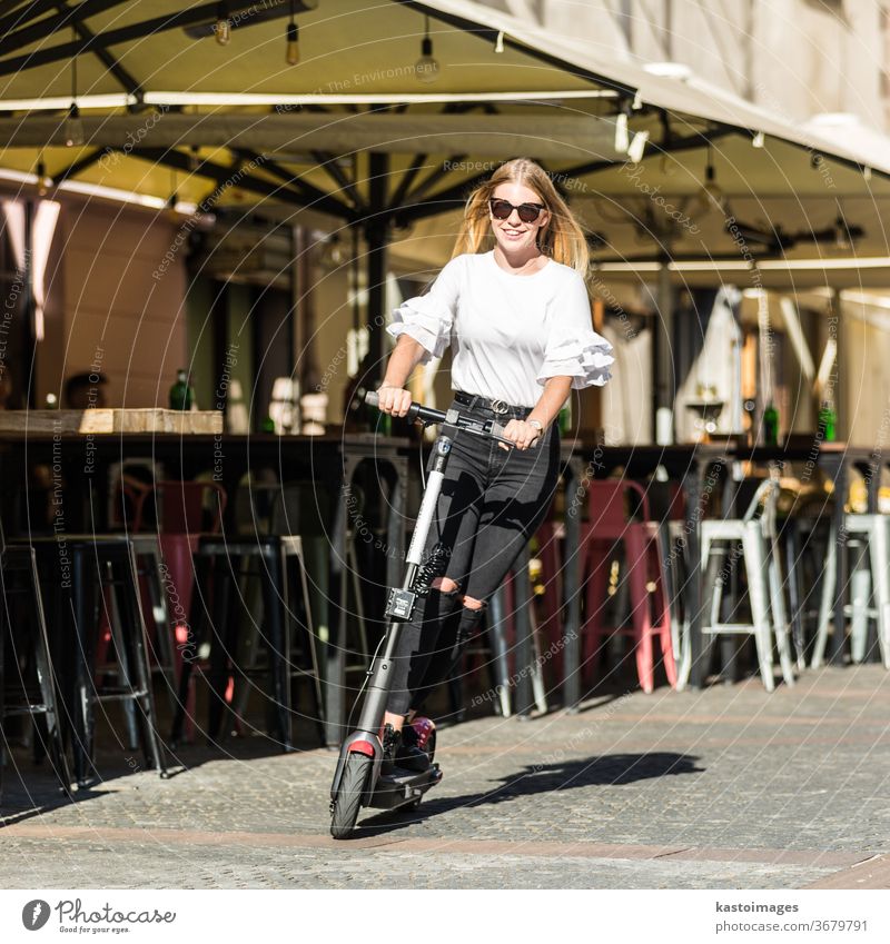 Trendy fashinable teenager girls riding public rental electric scooters in urban city environment. New eco-friendly modern public city transport in Ljubljana, Slovenia