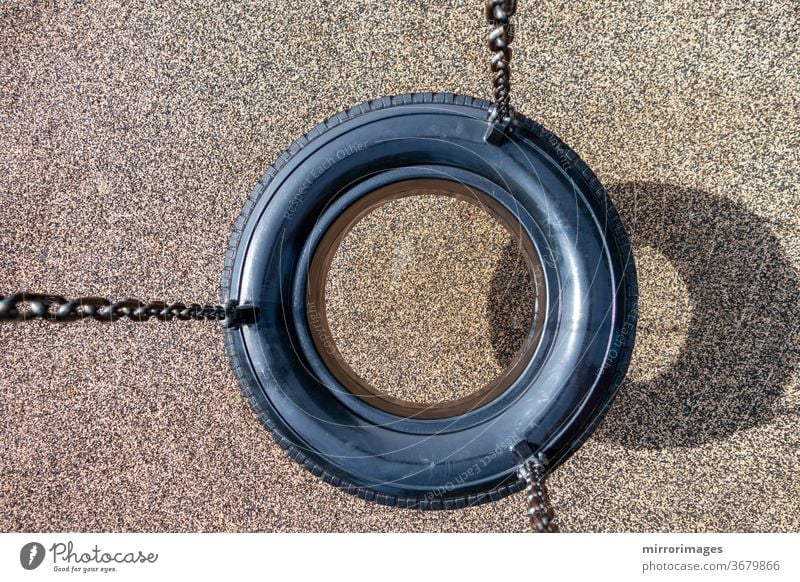 Overhead view of black chain Tire Swing at a children's  play ground no people activity background black chain tire swing chains childhood children swing empty