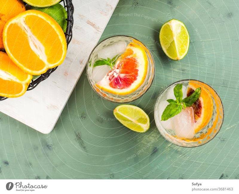 Fresh summer citrus drink with ice on green water cocktail lemonade detox mocktail blood orange fruit flat lay top view lime juice mint soda infused sweet