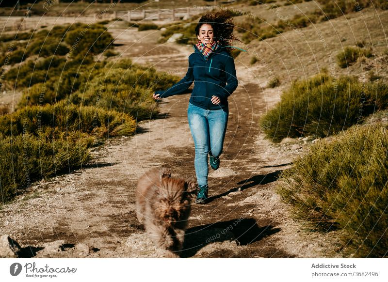 Woman and dog running in countryside woman path fun follow weekend puerto de la morcuera spain female labradoodle sunny daytime happy smile cheerful lifestyle