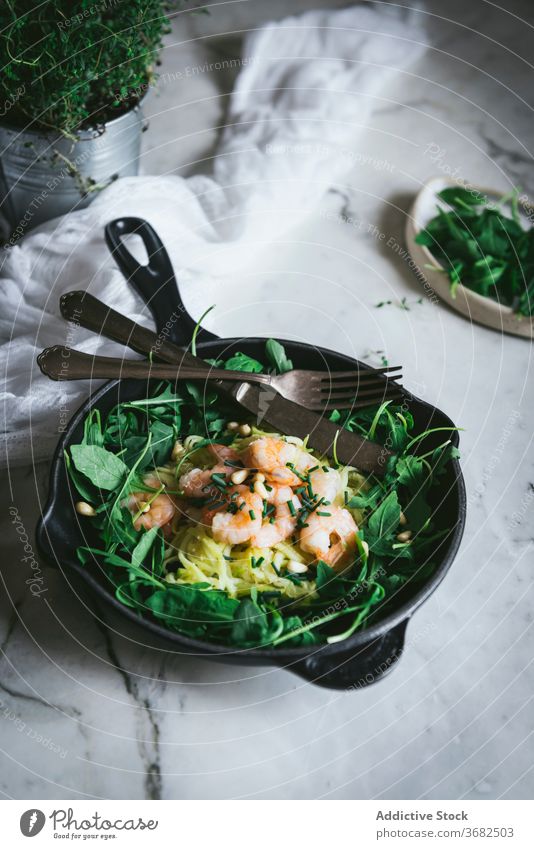 Zucchini noodles with spinach and prawns dish table pan utensil kitchen zucchini portion delicious fresh knife fork marble food meal tasty cuisine organic