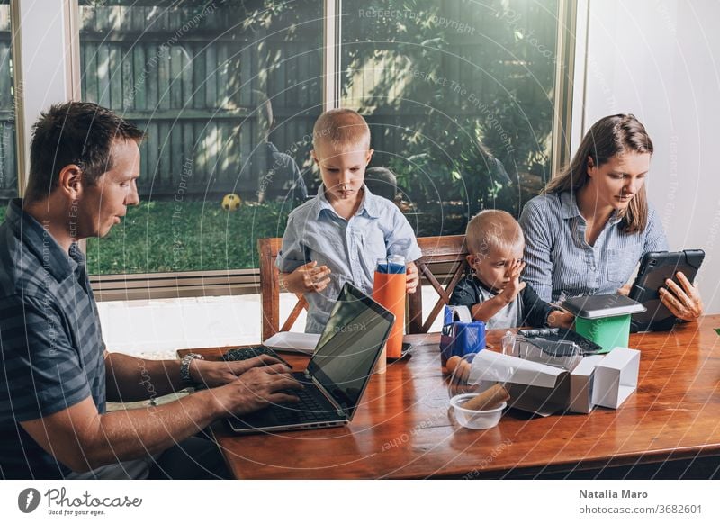 Concept of work from home and home family education. Parents and two sons are sitting at the desk. parent laptop kid office recycled craft business child