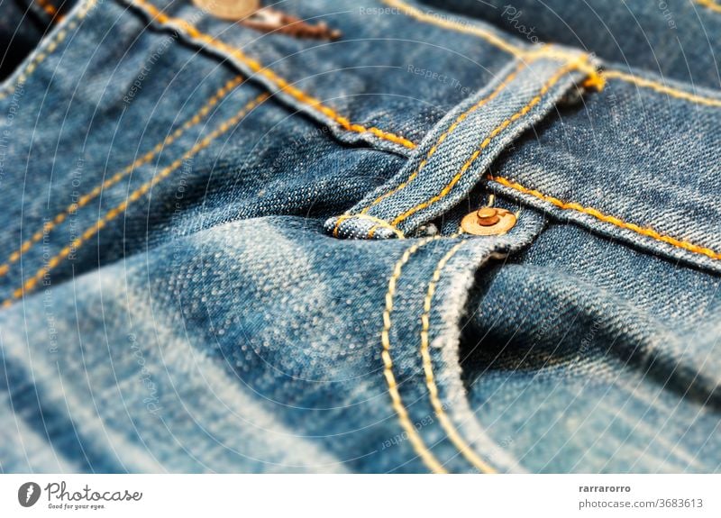 close-up view of the copper rivet on the pocket of a pair of denim trousers jeans canvas fabric texture blue fashion clothing clothe design pattern material