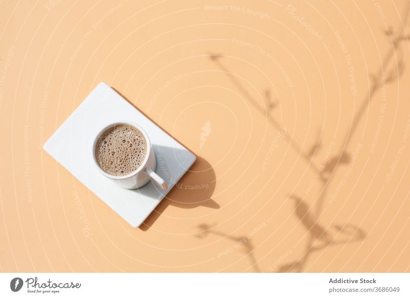 Cup of coffee on beige table cup drink aroma fresh hot mug beverage natural morning caffeine shadow sunlight plant branch breakfast delicious energy espresso