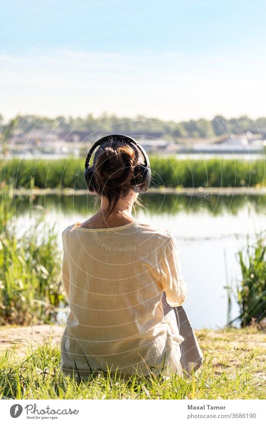 Woman with headphones is meditating, sitting in front of the river,  just after the sunrise. adult beautiful beauty body calm caucasian concentration energy