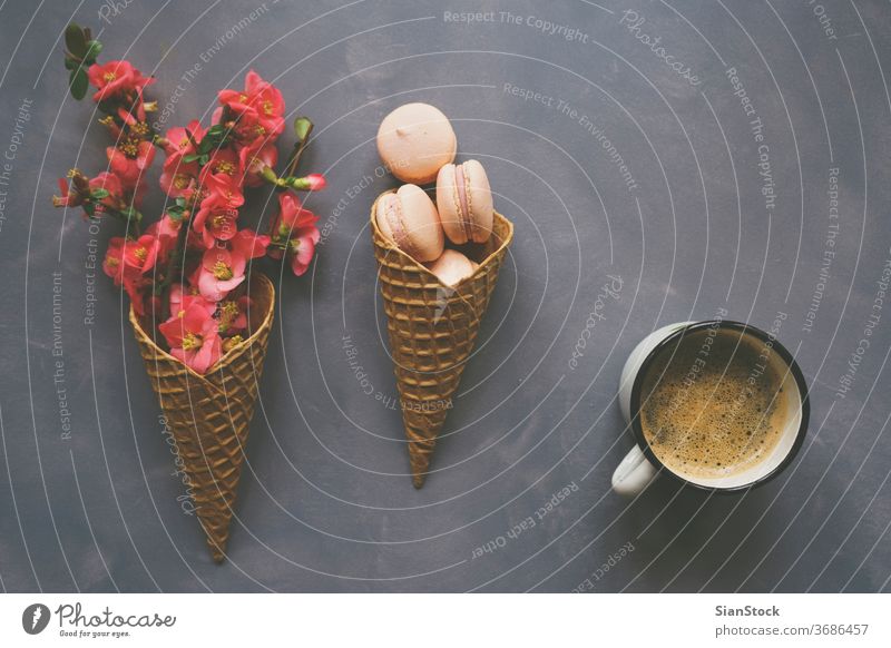 Coffee, macarons and flowers in ice cream cone on cement background coffee morning top macaroon view table cup white lay flat desk pink breakfast above spring