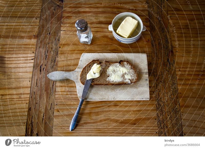 Snack, bread, butter and salt with snack board on a wooden table. Bread and butter Butter Salt vesper board Wooden table Rustic Rural Knives Mixed-grain bread