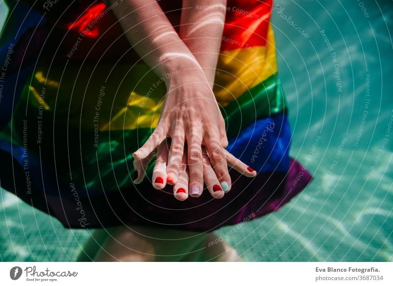 two women at the pool together wrapped with rainbow gay flag. LGBT concept love lesbian underwater swimming pool floating summer lgbt dating romantic bisexual