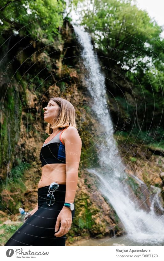Young female nature explorer standing by the waterfall achievement active adult adventure awe cascade caucasian destination enjoying enjoyment environment
