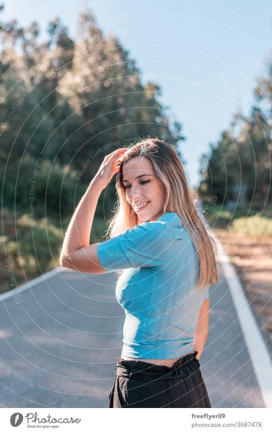 Portrait of a young and attractive caucasian woman near a forest portrait 20s road exterior outdoors lifestyle blonde desaturated retro copy space countryside