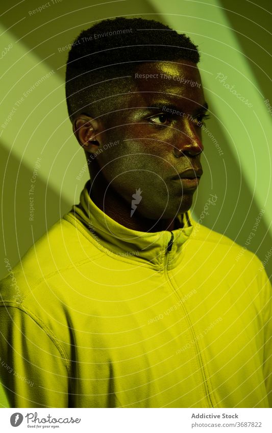 Serious ethnic sportsman in studio with neon lights athlete confident serious green shadow determine stripe brutal active physical young black african american