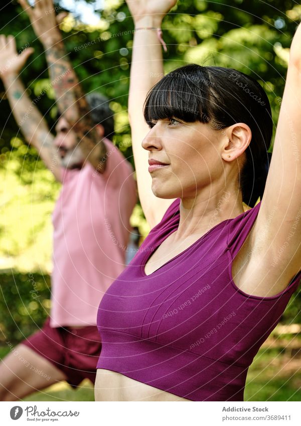 Calm couple practicing yoga in crescent pose together crescent variation lunge high lunge park barefoot sunny training relationship tranquil healthy serene