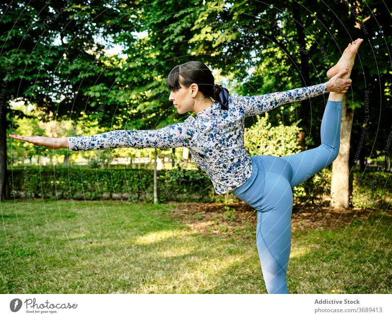 Woman doing yoga in Lord of the Dance pose in park lord of the dance woman flexible asana natarajasana concentrate calm female nature healthy practice sunny