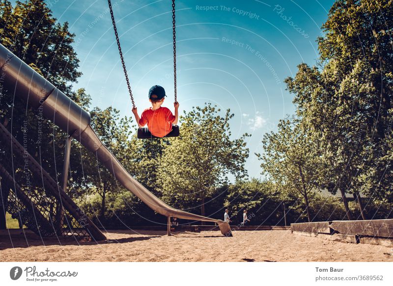 Boy on a swing on the playground Boy (child) Child rock Swing Playground Playing Tall Chain Adventure foolhardy cap from behind Slide Comical muck about huts