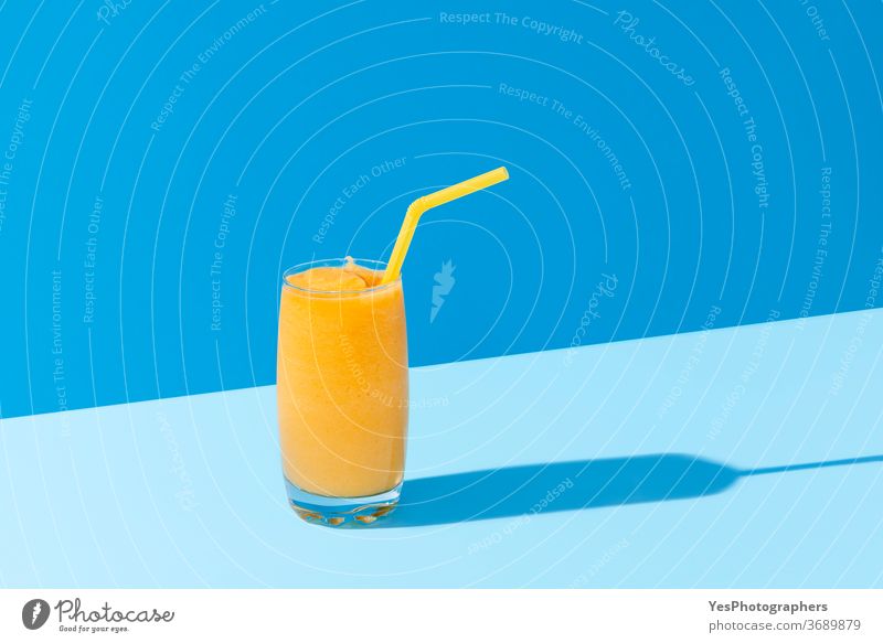 Mango smoothie on blue color. Summer drink. Mango shake with a straw background beverage bright cocktail cold colors copy space cut out delicious dessert detox